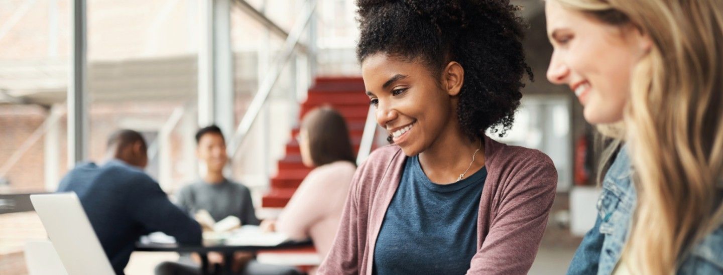 Happy Female students look at laptop