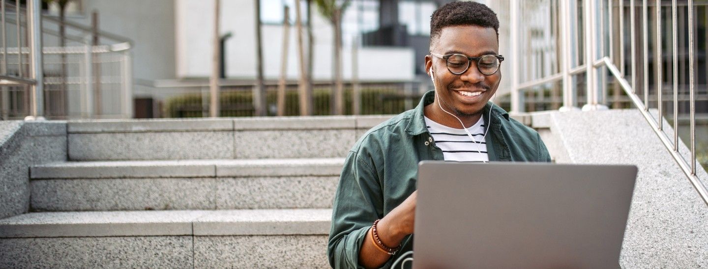 Man works on laptop outdoors on stairs