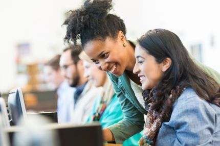 Two happy women converse over computer screen