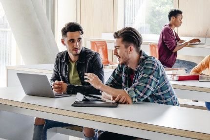 Two men in class having discussion with laptop