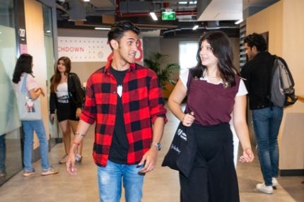 Two students walk and talk on campus