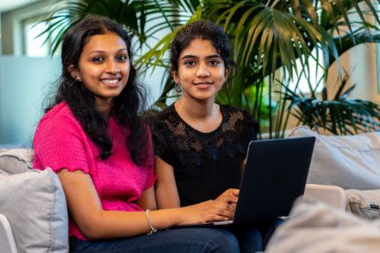 Two women work on laptop in reception area