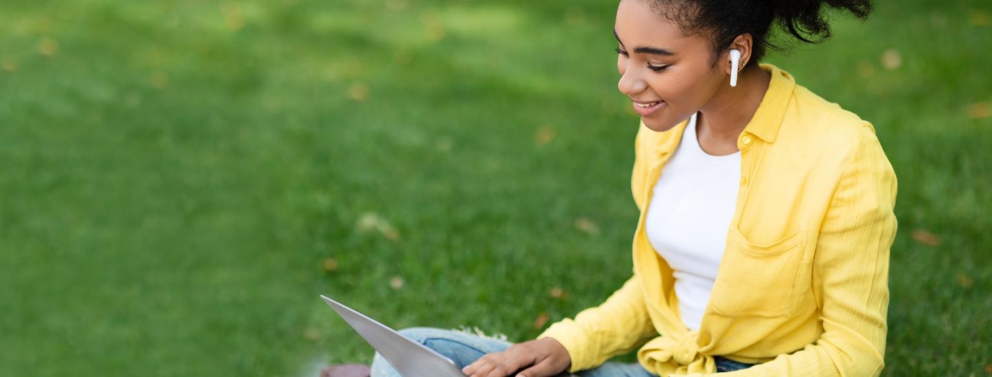 Woman studying outside on grass
